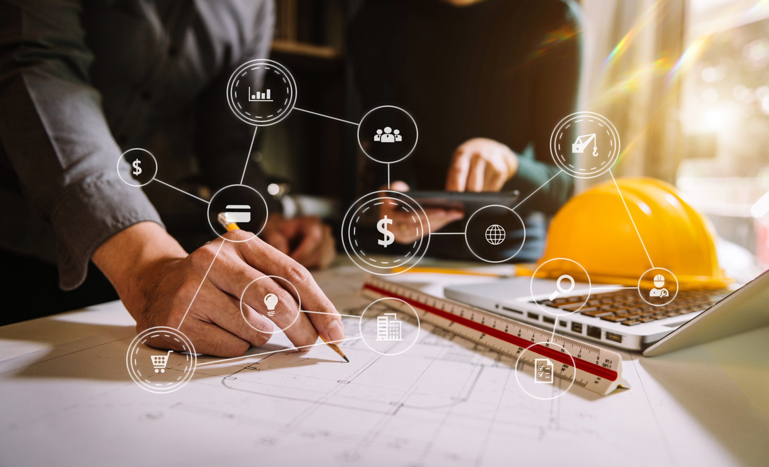 Two colleagues, data and money icons, tablet and laptop on desk in office.