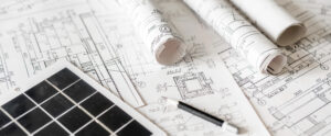 Architectural blueprints with rolled plans and solar panel, sustainable architecture and green building design, renewable energy integration, construction planning background.