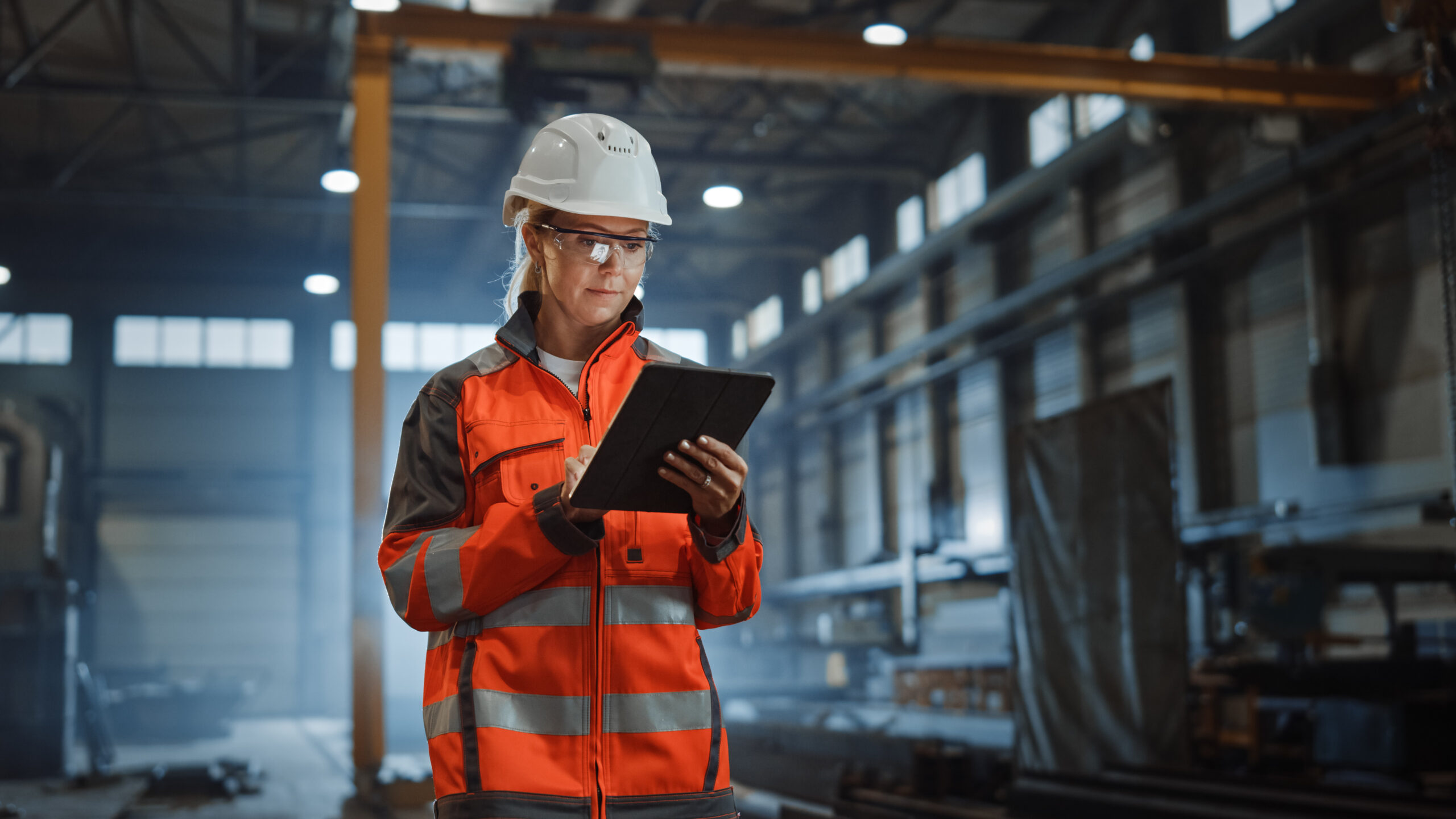 Professional Heavy Industry Engineer Worker Wearing Safety Uniform and Hard Hat, Using Tablet Computer.