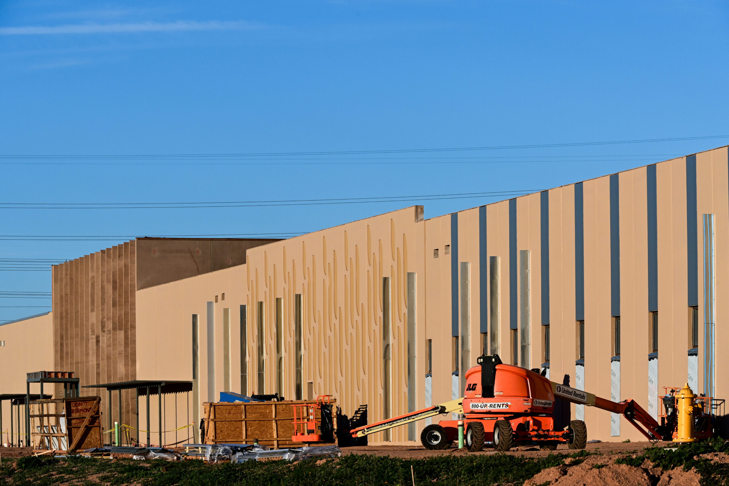 Large-scale data center under construction with prefabricated concrete panels and heavy equipment.