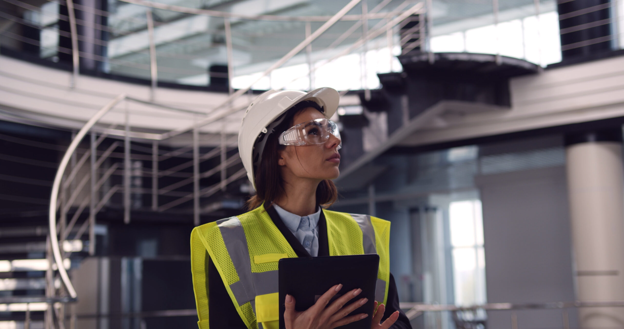 Close up of female architect standing inside empty office center holding a tablet checking building plan.