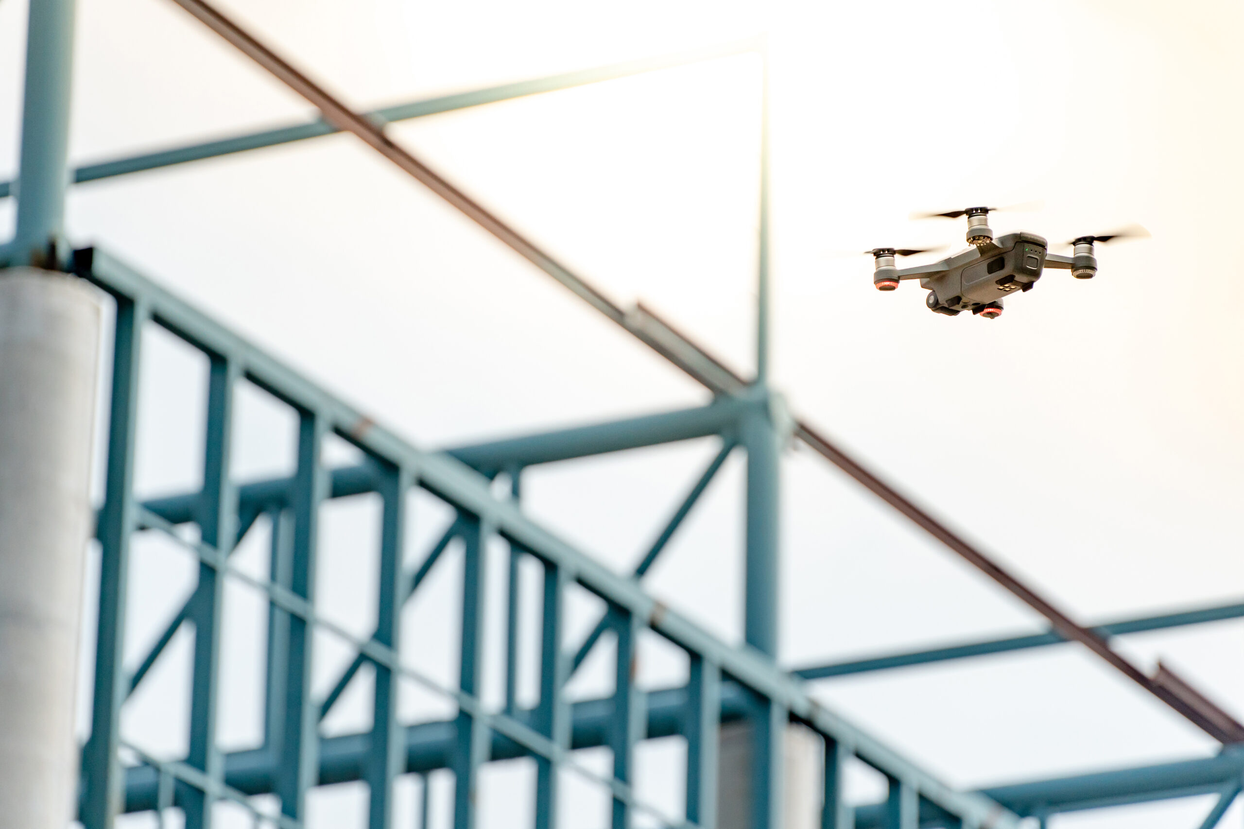 Drone flying over steel structure at construction site.